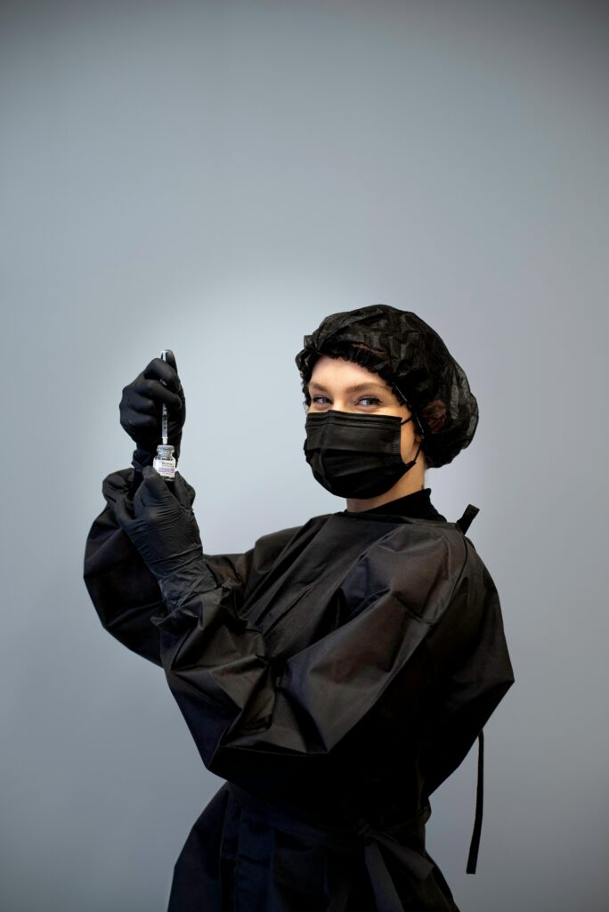 pexels-photo-18809796-18809796 Beautician in black uniform and mask prepares syringe, exemplifying hygiene.